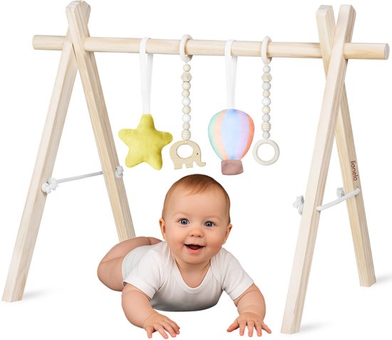 Baby ligt onder houten babygym met gele ster, houten olifant, ballon en ring. Baby draagt een wit rompertje.
