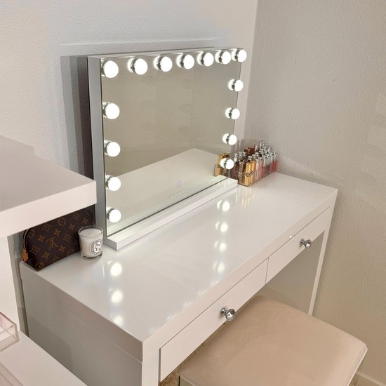 Witte make-upspiegel met verlichting, op een witte console met make-up en een tas.