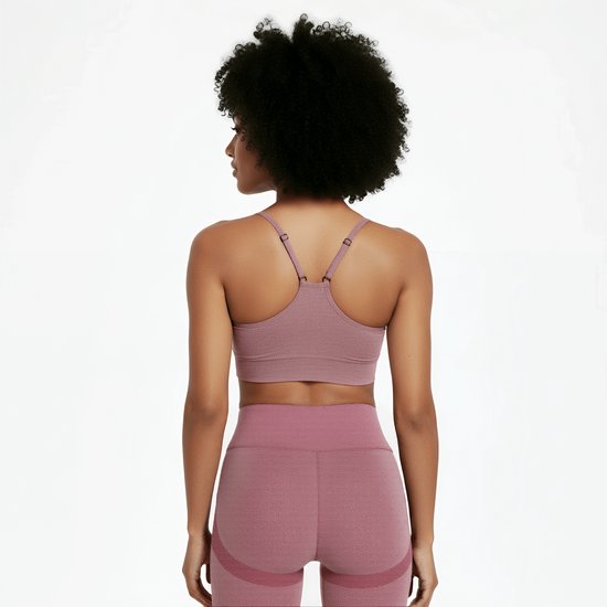 Vrouw met afro haar, van achteren gezien, draagt een roze sportbeha en legging.