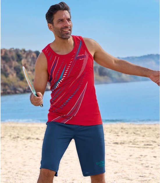Man op strand in rood sportshirt met blauwe print en een marineblauwe sportshort met 'SPORT TEAM' logo.