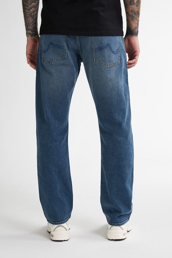 Achterzicht van een blauwe spijkerbroek met rechte pijpen, gedragen met sneakers.