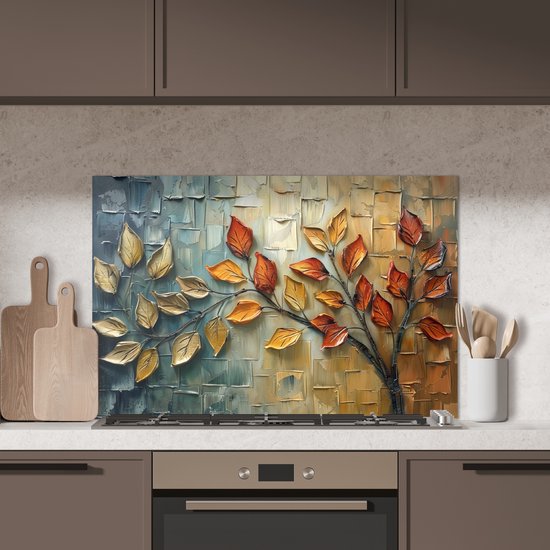 Keukenspatscherm met abstracte boom, gouden en oranje bladeren. Geplaatst boven een gasfornuis met houten snijplanken ernaast.