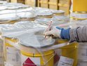 Hand met werkhandschoen kleurt "3x5" op deksel van gele ton met rode edding 3000 marker.