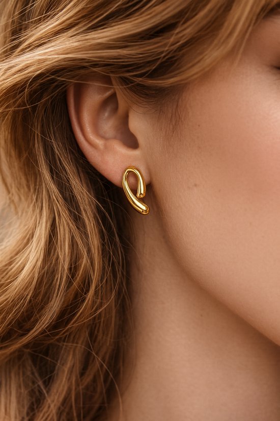 Mannequin portant une boucle d'oreille dorée à la forme torsadée et incurvée.