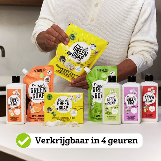 Een man met een witte trui toont Marcel's Green Soap producten in sinaasappel & jasmijn geur: flessen, navulverpakkingen en tabletten.
