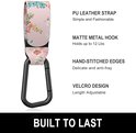 Roze kinderwagenhaak met bloemenprint, zwarte metalen karabijnsluiting, met tekst over PU-leer, haak, stiksels en klittenband.