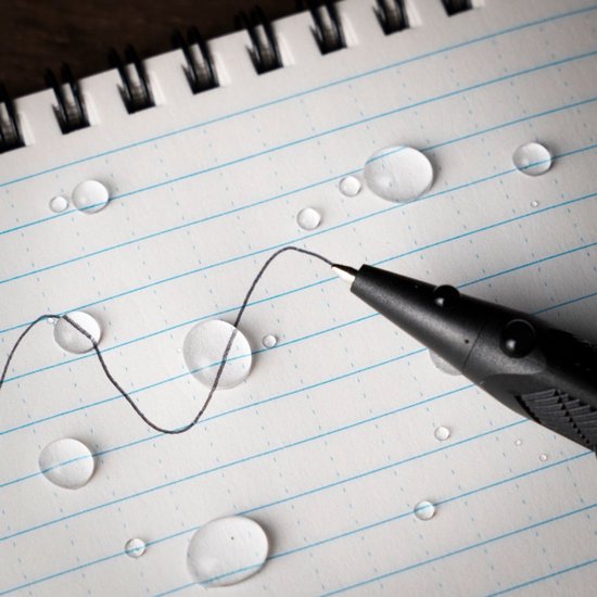 Lined schrijfblokpagina met een pen die een golvende lijn tekent. Waterdruppels op de pagina.