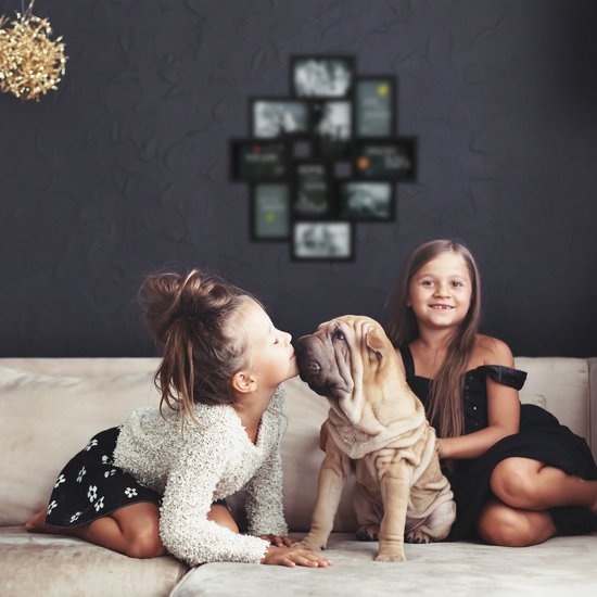 Twee meisjes en een puppy op een bank, met een zwarte fotolijst-collage op de muur.