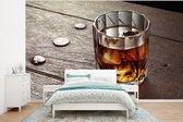 Behang - Fotobehang Glas met whisky op een houten tafel - Breedte 350 cm x hoogte 260 cm