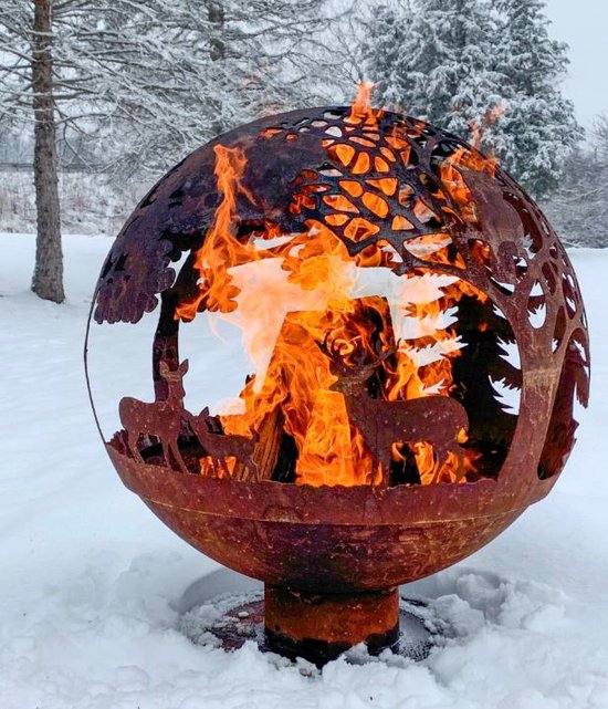 Roestbruine vuurschaal in bolvorm met open gesneden dieren en bomen, brandend in de sneeuw.