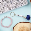 Roze kralen armband 'HAPPY' en sleutelhanger 'SMILE' gemaakt van witte letterkralen.