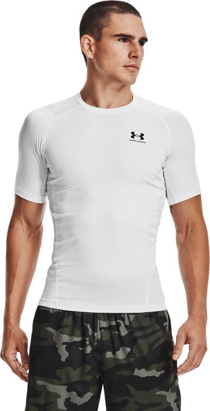 Man draagt een wit sportshirt met korte mouwen, met een zwart Under Armour logo op de borst.