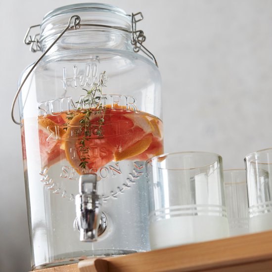 Glazen drankdispenser met 'Hello Summer' opdruk, gevuld met water, partjes grapefruit en kruiden.