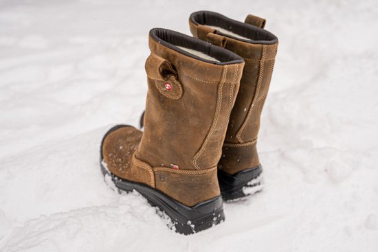 Paar bruine leren werklaarzen in de sneeuw, met Sixton logo en dikke zool.