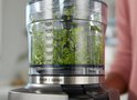 Close-up van een Kenwood chopper met fijngehakte kruiden, tot 500 ml.