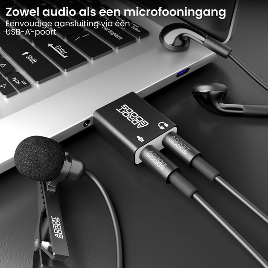Zwarte USB-geluidskaartadapter op een laptop, met aangesloten microfoon en oortjes.