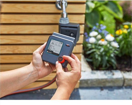 Handen bedienen GARDENA besproeiingscomputer met digitaal scherm en draaiknop.