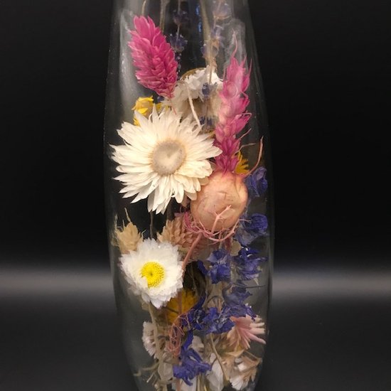 Gedroogde bloemen in een glazen fles met kurk. Witte, roze, blauwe en gele bloemen.