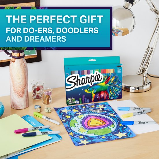 Een bureau met een Sharpie marker set, inclusief een doos met 18 markers en een vis design. Tekeningen en kantoorbenodigdheden liggen verspreid.