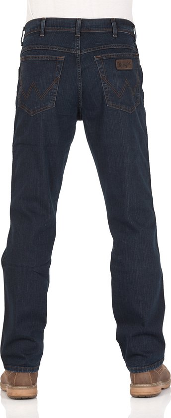 Achterkant van een man in een donkerblauwe Wrangler jeans met bruine schoenen.