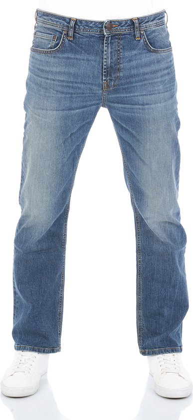Model in een rechte blauwe denim jeans met lichte wassing en witte sneakers.