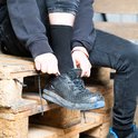 Man met zwarte werksokken strikt blauw-zwarte werkschoenen