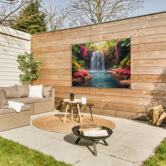 Une affiche représentant une cascade de jungle avec des fleurs roses et de l'eau bleue, accrochée à une clôture en bois sur une terrasse avec des meubles de jardin.