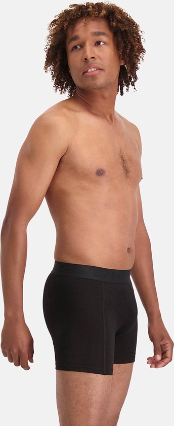 Man met krullend haar in een zwarte bamboe boxershort, kijkt naar rechts.