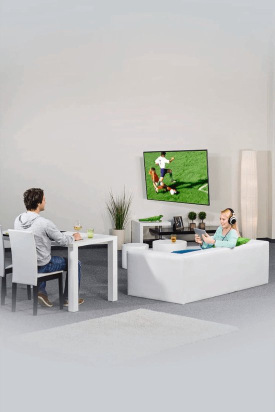 Mannen en vrouwen kijken tv in een modern ingerichte woonkamer, met een witte bank en tafel.
