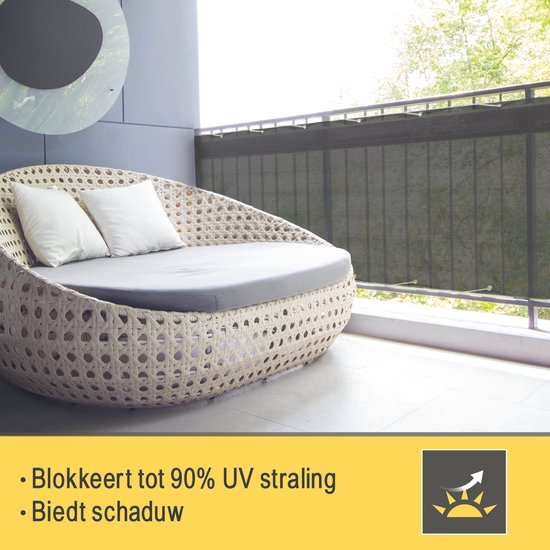Balkon met wicker loungemeubel en donkergrijs balkondoek. "Blokkeert tot 90% UV straling. Biedt schaduw".