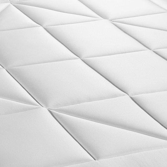 Detailopname van het witte, gewatteerde matras met ruitpatroon.