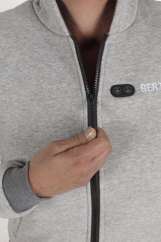 Close-up van een hand die de rits van een grijze hoodie sluit.