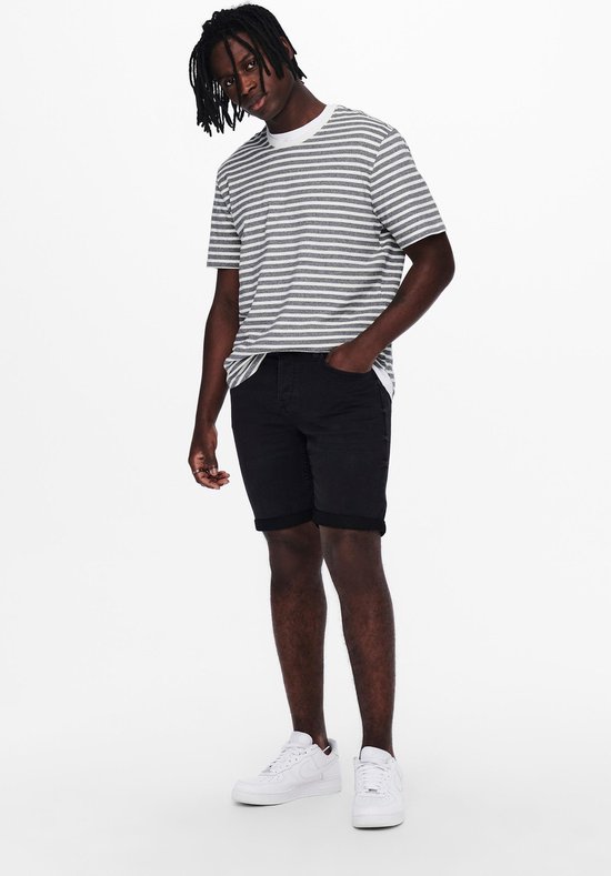 Man met gestreept t-shirt en zwarte denim shorts, witte sneakers.