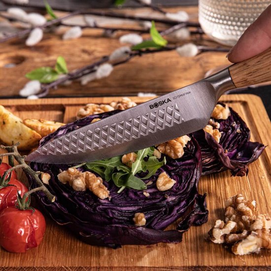 Boska RVS steakmes met houten handvat snijdt door rode kool, gegarneerd met walnoten.