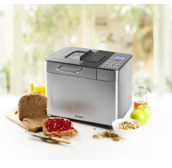 RVS broodmachine met brood, ontbijtgranen, sap en fruit in een keuken.