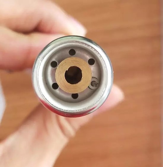 Zilverkleurige bovenkant van de brander met gouden ring en zes kleine ronde gaten.