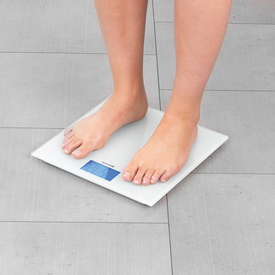 Pieds sur une balance personnelle numérique blanche avec écran bleu.