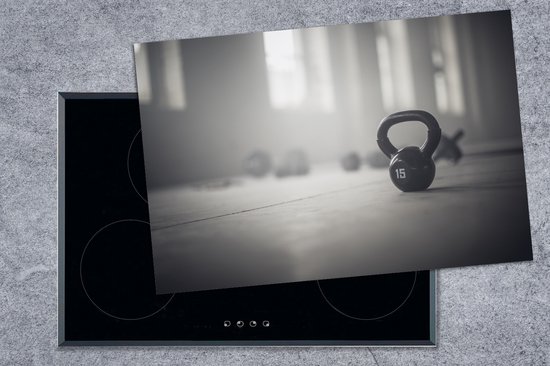KitchenYeah® Inductie beschermer 76x51.5 cm - Verschillende kettlebellgewichten op de vloer in een fitnessruimte - Kookplaataccessoires - Afdekplaat voor kookplaat - Inductiebeschermer - Inductiemat - Inductieplaat mat