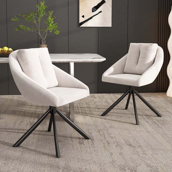 Deux chaises en velours beige avec coussins lâches sur pieds noirs à côté d'une table à manger.