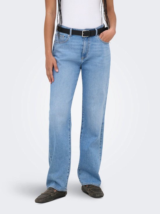 Model met een lichtblauwe mom fit jeans met rechte pijpen, riem en loafers.