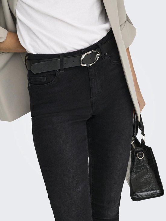 Close-up van de tailleband van een zwarte skinny jeans met een zwarte riem met ovale gesp.