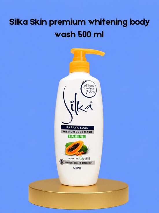 Witte fles met oranje pompdispenser, "Silka Papaya Luxe" bodywash, 500ml, op een gouden standaard met blauwe achtergrond.