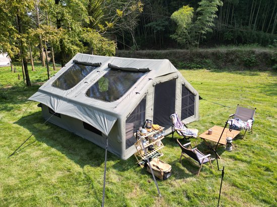 Ruime legergroene opblaasbare tent met twee ramen en twee deuren, opgezet op een grasveld.