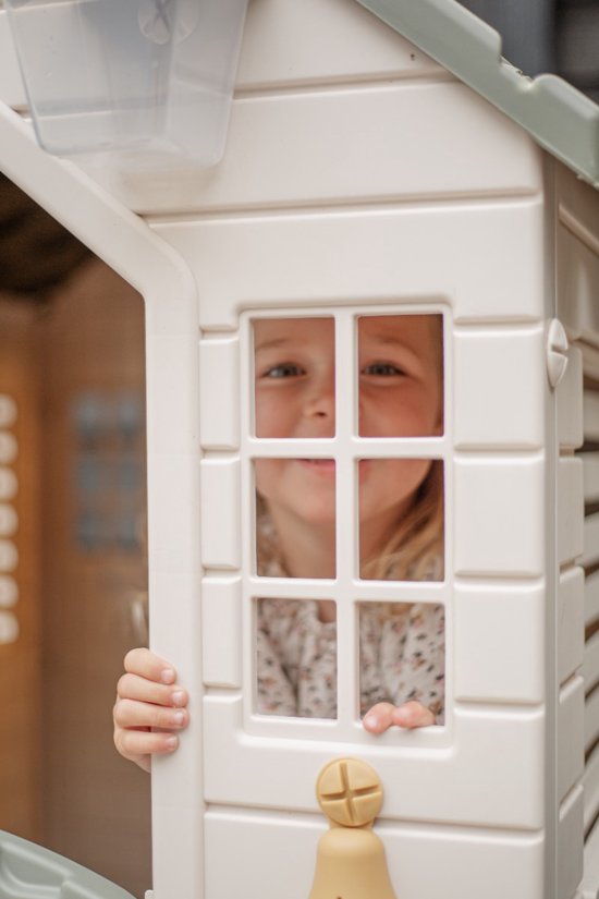 Meisje met gebloemd jurkje kijkt door crème speelhuisje met wit raam met vakverdeling.