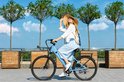 Vrouw met strooien hoed rijdt op een hemelsblauwe elektrische fiets.