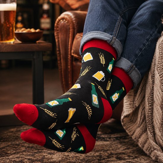 Zwarte sokken met bierpatroon, gedragen door een persoon die ontspant in een leren fauteuil.