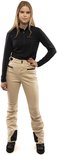 Model in een beige skibroek met zwarte top, staand met een hand op de heup.