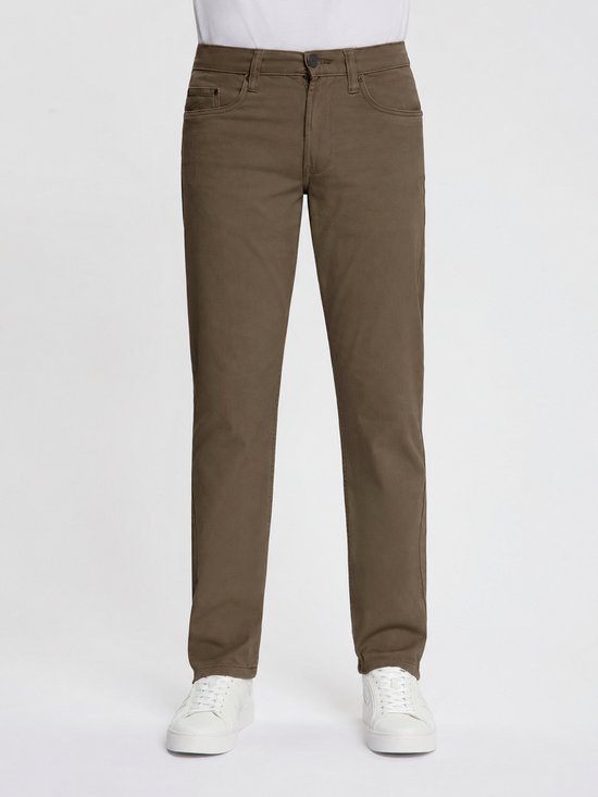 Man in witte T-shirt, khaki broek en witte sneakers, staand. Volledige voorkant zichtbaar.