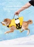 Hand tilt hond met bijen-zwemvest bij de ruggreep boven het water.