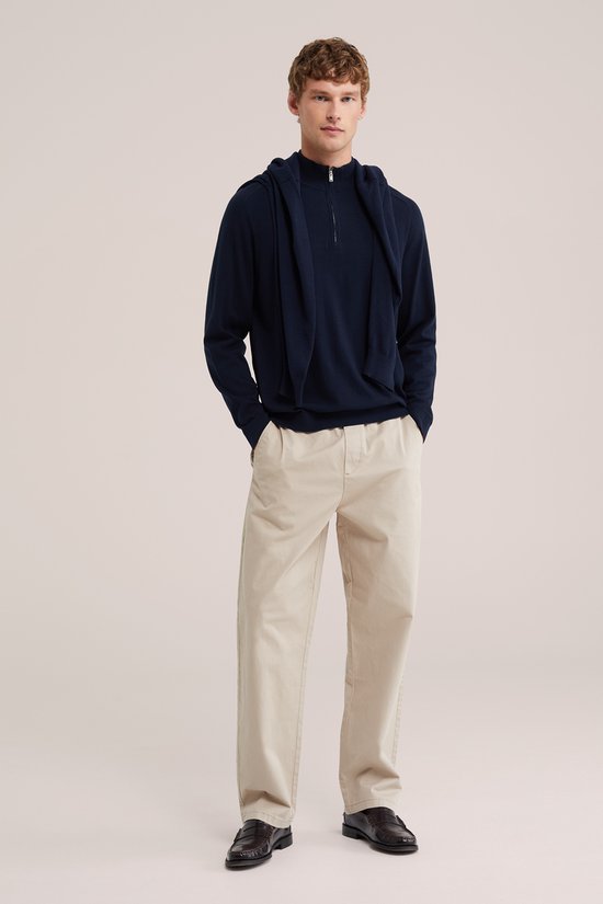Een man met een donkerblauw trui en beige chino met elastische tailleband.
